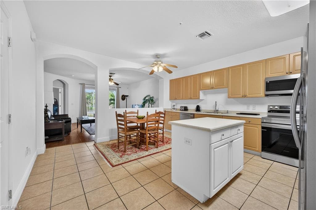 Large Kitchen, Center Island, featuring light countertops, New and newer appliances with stainless steel finishes, arched walkways, light tile patterned floors, and ceiling fan