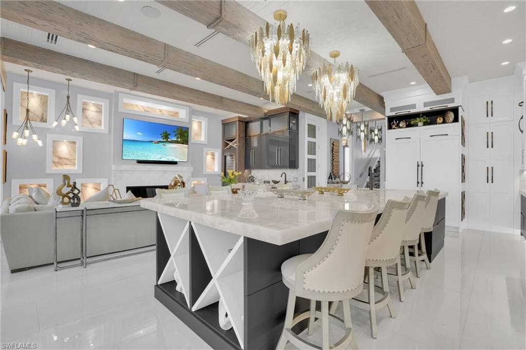 Kitchen featuring open shelves, a chandelier, white cabinets, a breakfast bar, and beam ceiling - Virtually Edited Image