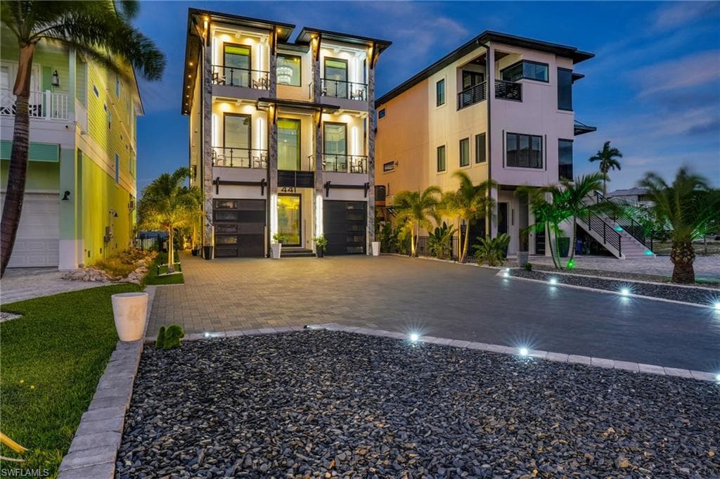 View of front of house featuring stucco siding, decorative driveway, stairs, and an attached garage