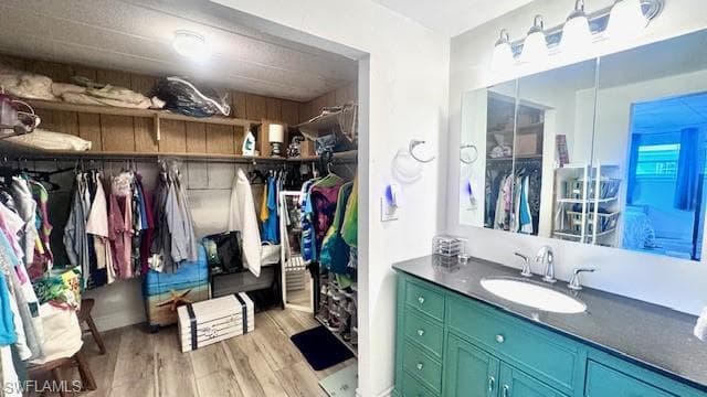 Ensuite bathroom featuring a walk in closet, vanity, and light wood finished floors