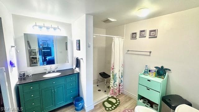 Bathroom featuring a shower stall, vanity, and light wood-style flooring
