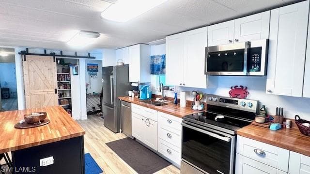 Kitchen featuring butcher block countertops, a barn door, and stainless steel appliances