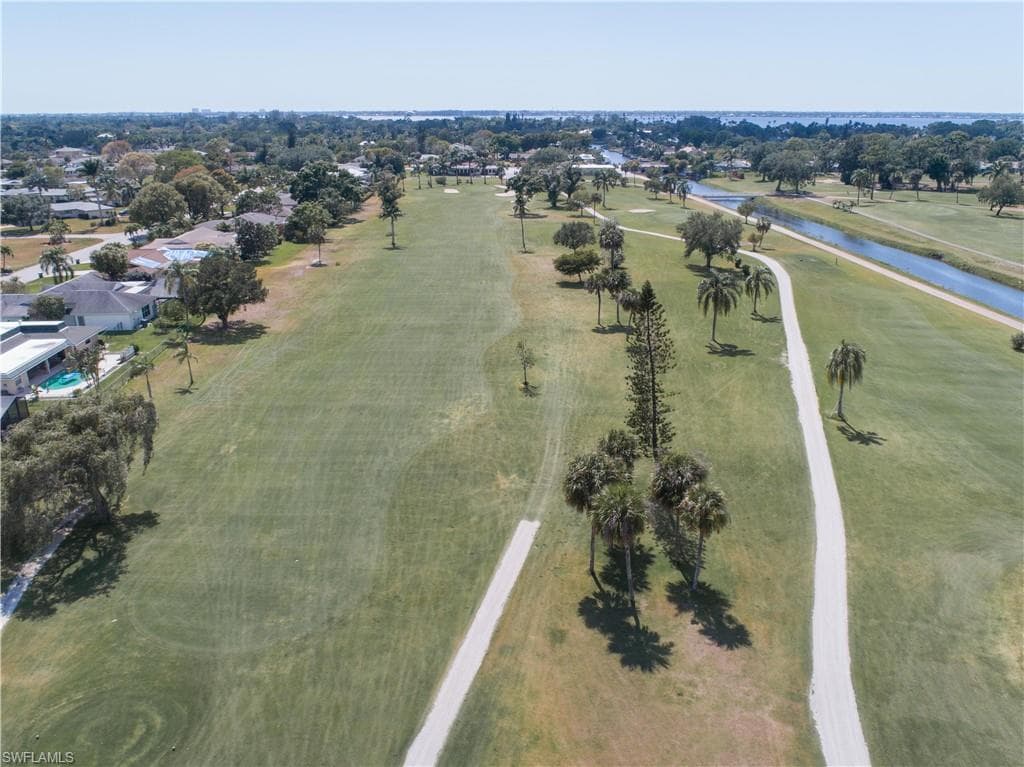Aerial view of property and surrounding area with a nearby body of water and a golf club