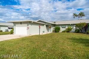 Ranch-style home featuring a garage, concrete driveway, and a front lawn