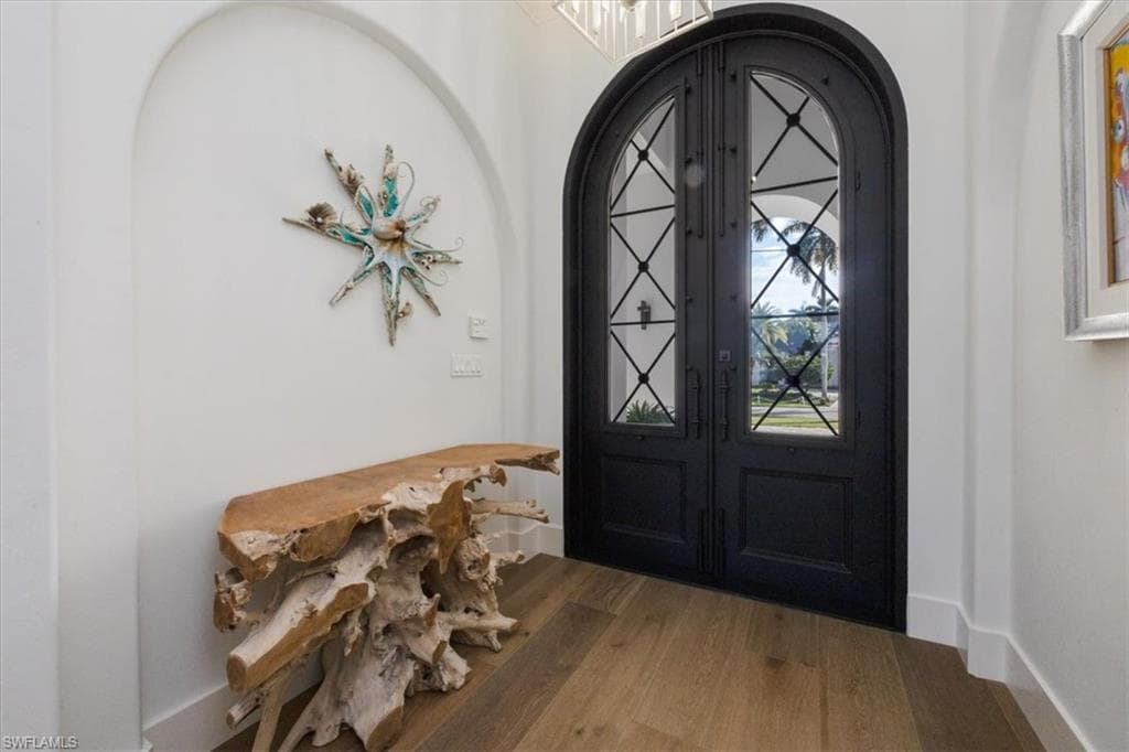Foyer entrance featuring arched walkways, wood finished floors, and french doors