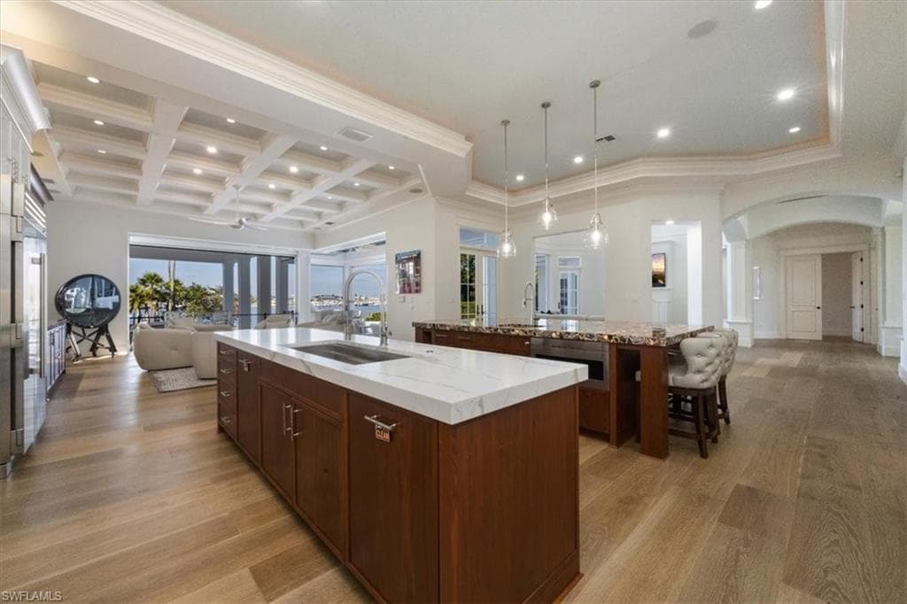 Kitchen with open floor plan, recessed lighting, coffered ceiling, hanging light fixtures, and arched walkways