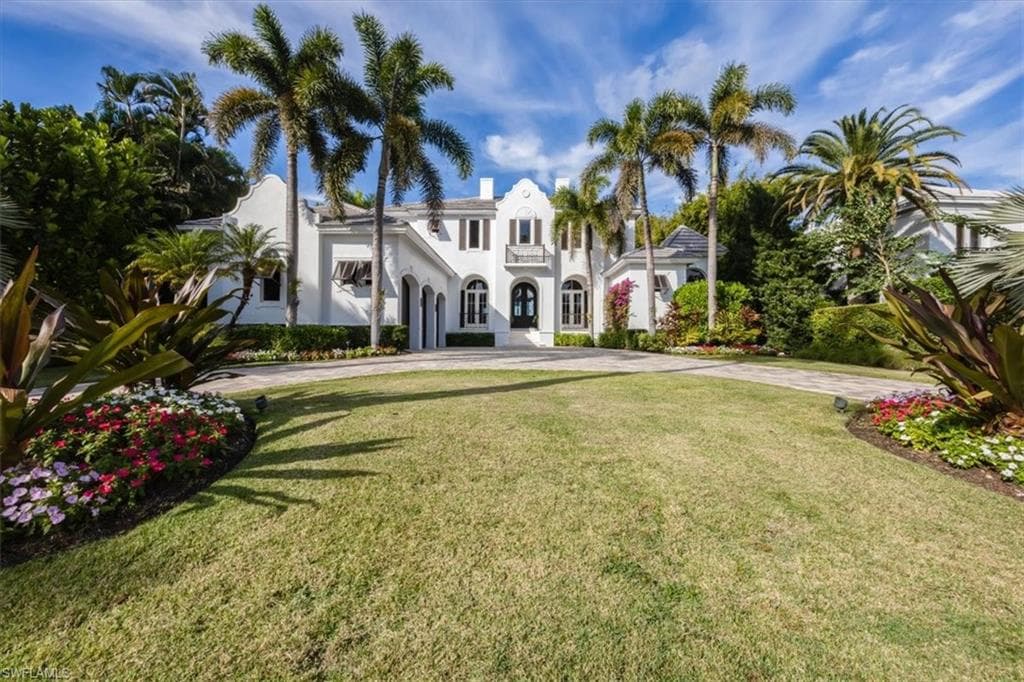 Mediterranean / spanish house with a front yard, stucco siding, and driveway