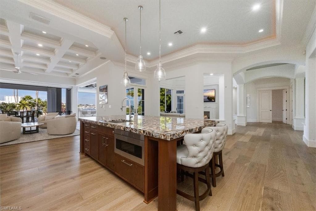 Kitchen with open floor plan, arched walkways, pendant lighting, coffered ceiling, and recessed lighting