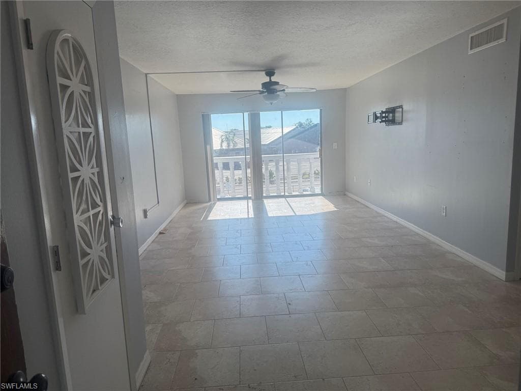 Empty room with a textured ceiling and ceiling fan