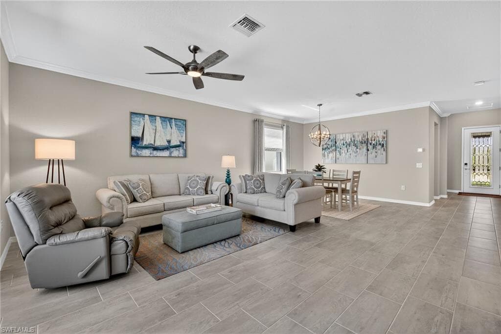 Living room with ornamental molding, plenty of natural light, ceiling fan, and a chandelier