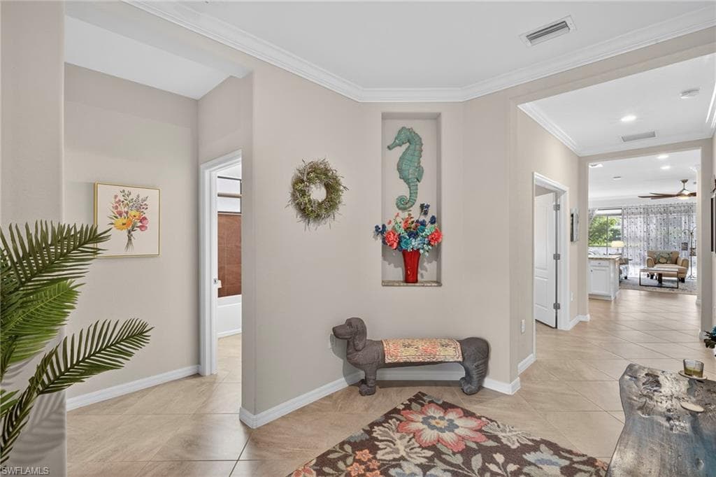 Hallway featuring ornamental molding and light tile patterned floors