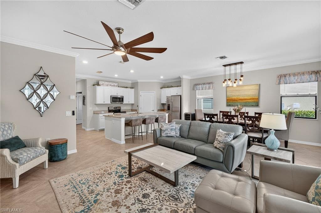 Living room featuring crown molding, a ceiling fan, and plenty of natural light