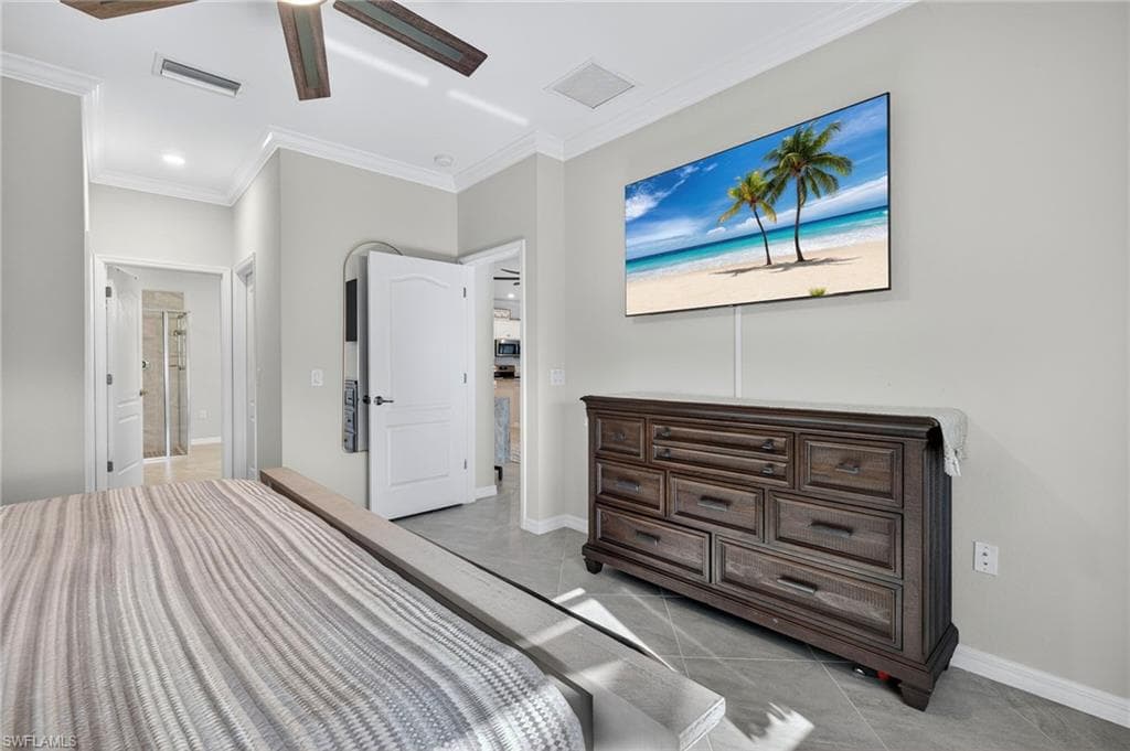 Bedroom featuring light tile patterned floors, ornamental molding, and ceiling fan