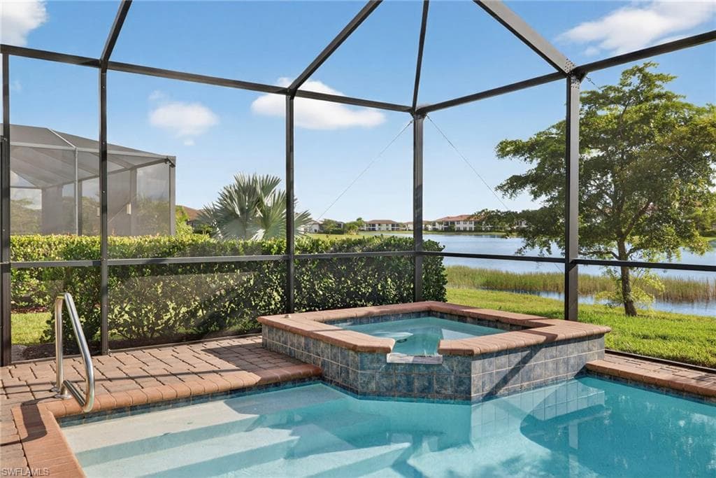 View of swimming pool with a sunroom, a water view, glass enclosure, and a pool with connected hot tub