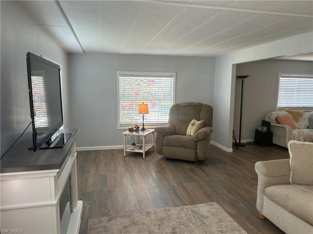 Living room with dark wood finished floors and healthy amount of natural light
