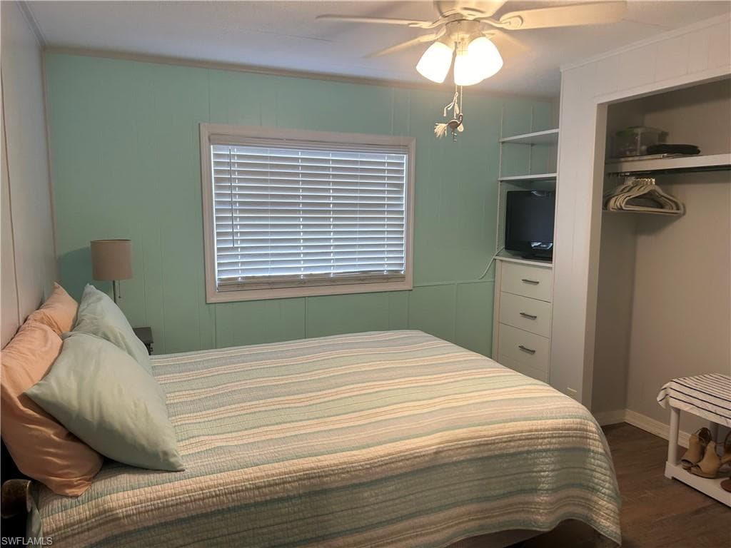 Bedroom featuring dark wood-style flooring, a ceiling fan, and ornamental molding