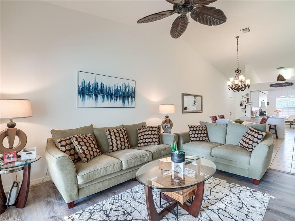 Living area featuring wood finished floors, a chandelier, a ceiling fan, and high vaulted ceiling