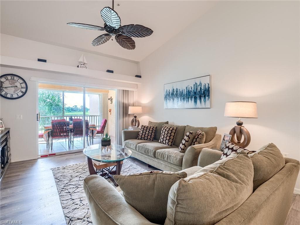 Living area with vaulted ceiling, a ceiling fan, and wood finished floors
