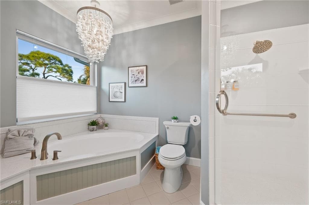 Full bath featuring a stall shower, light tile patterned floors, a bath, a chandelier, and crown molding