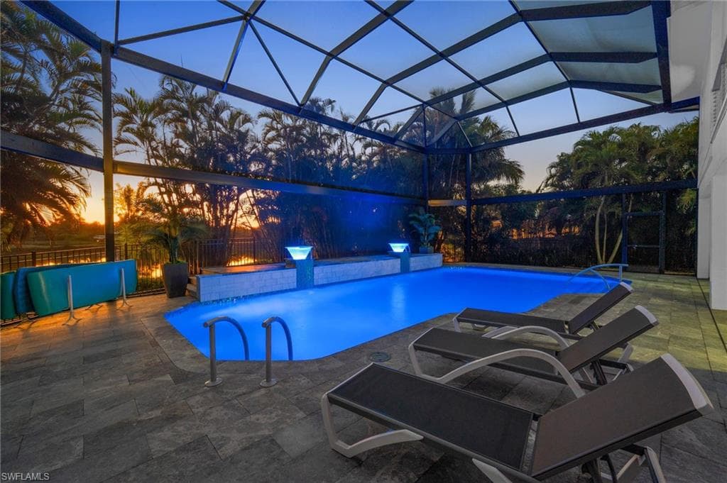 View of pool with screened enclosure, firery sunsets!!!, and a patio