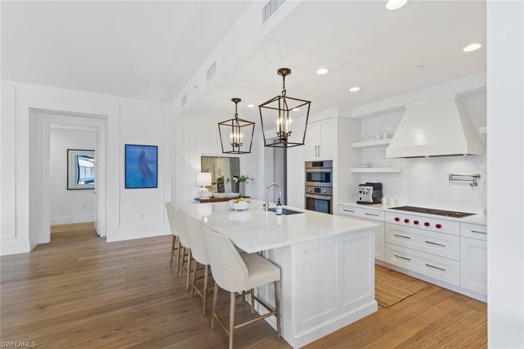 Kitchen featuring backsplash, decorative light fixtures, white cabinetry, a breakfast bar area, and recessed lighting