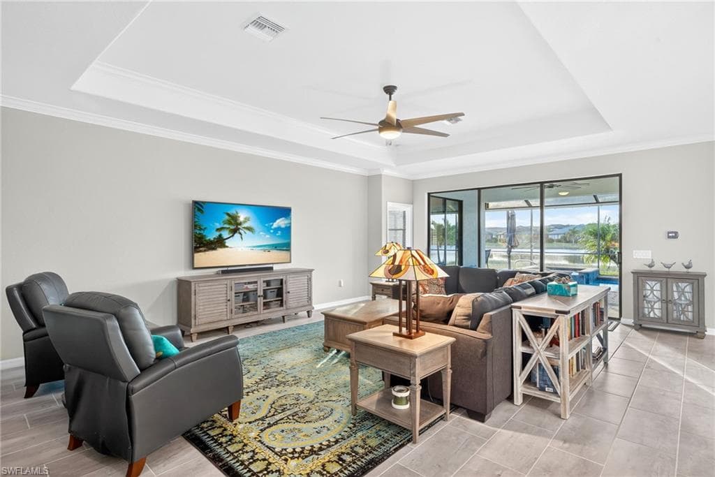 Living area featuring a tray ceiling, ornamental molding, and ceiling fan