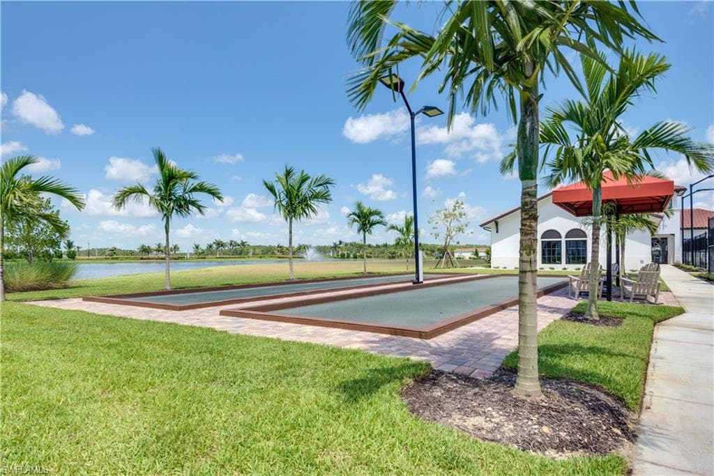 View of community featuring a lawn, a game area, a water view, and a patio area