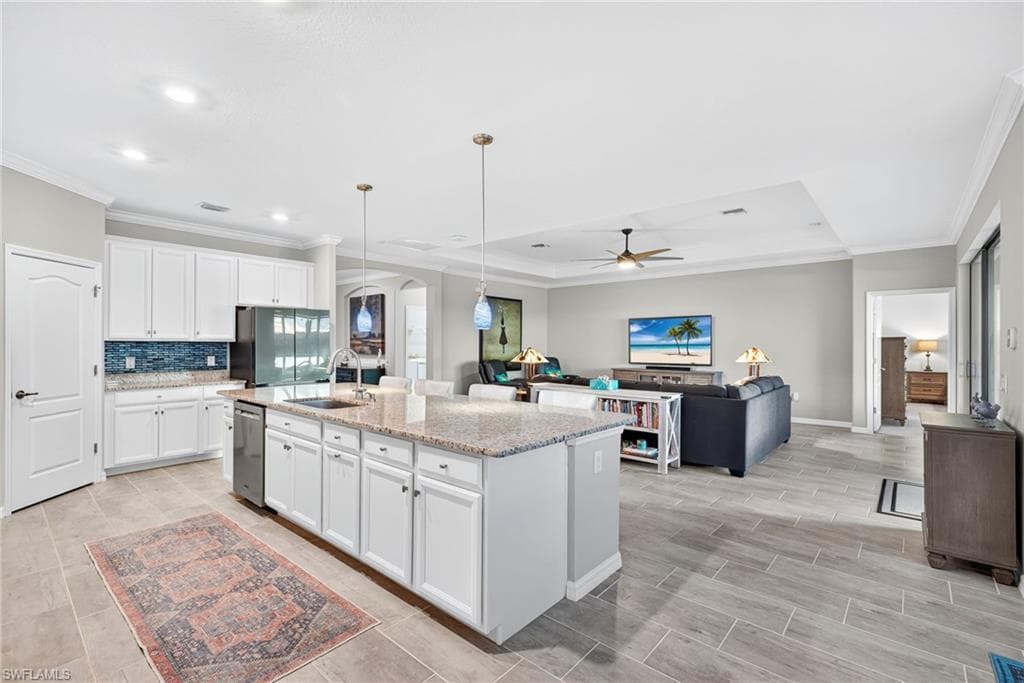 Kitchen featuring white cabinetry, pendant lighting, ceiling fan, light stone counters, and crown molding