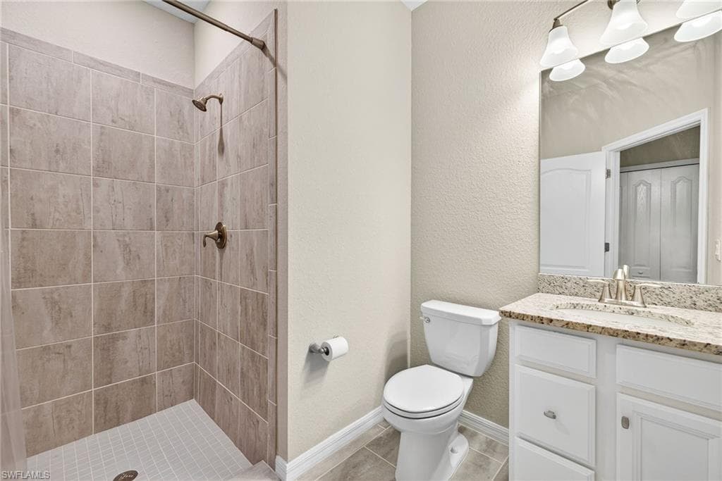 Full bath with vanity, a shower stall, and a textured wall