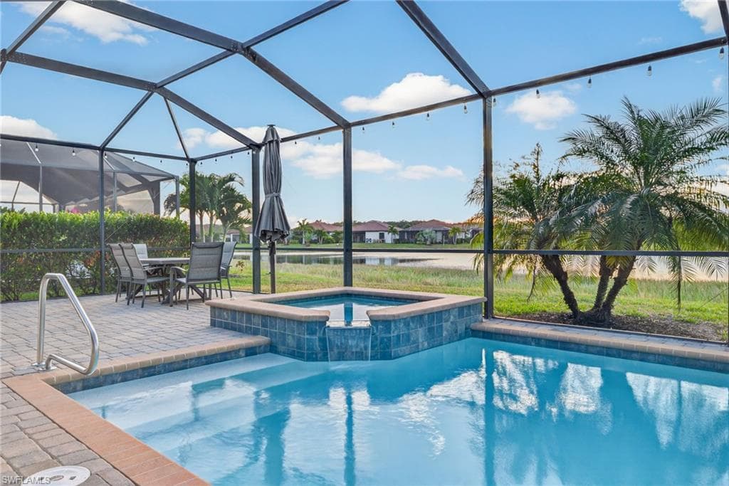 View of pool with a sunroom, a water view, a lanai, a pool with connected hot tub, and a patio area