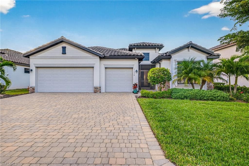 View of front of home featuring a front yard, decorative driveway, a tile roof, an attached garage, and stucco siding