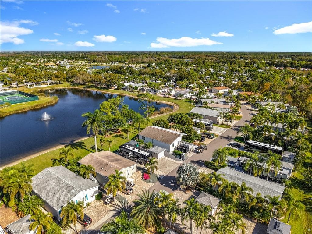 Aerial view of residential area with a nearby body of water and a tree filled landscape