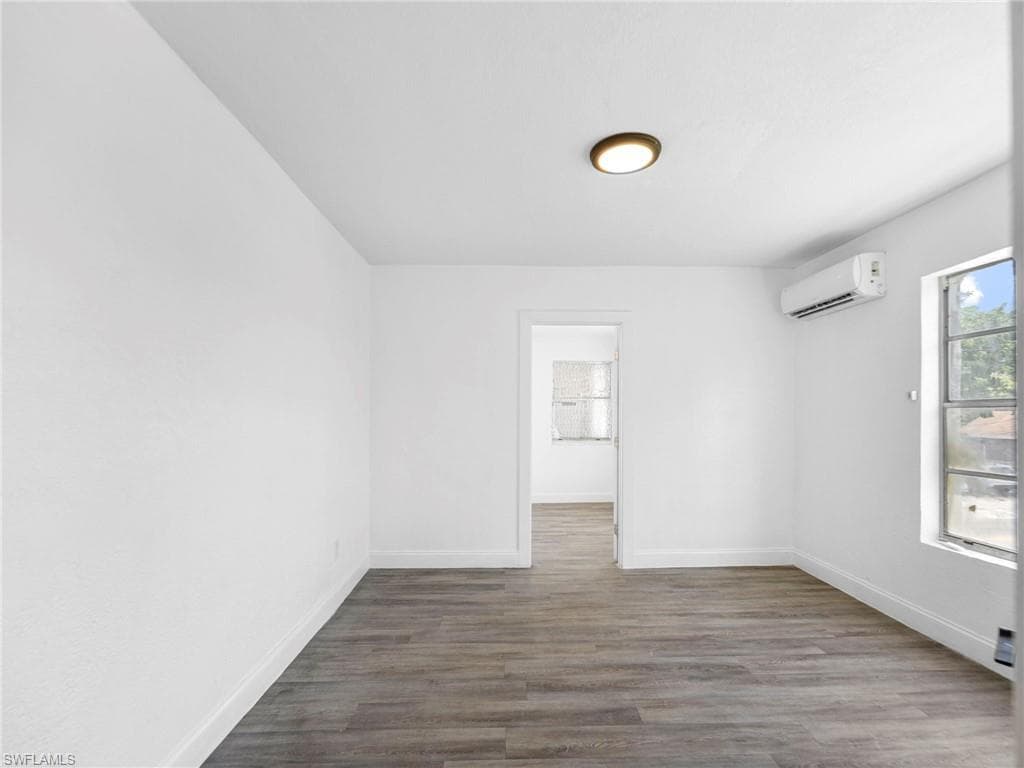 Unfurnished room featuring dark wood-style flooring and baseboards