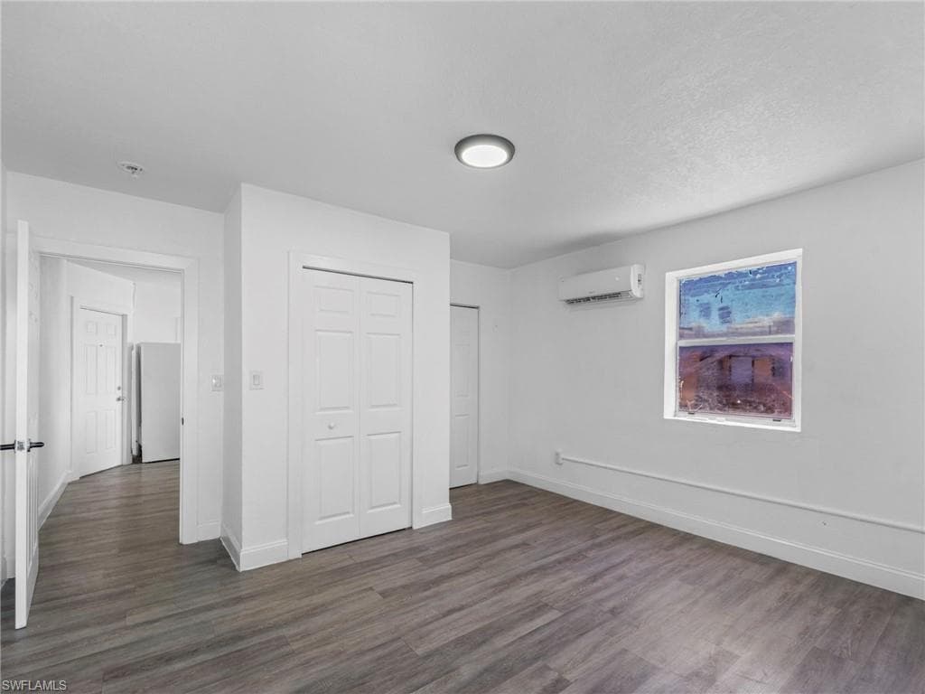 Unfurnished bedroom with dark wood-style floors and a closet