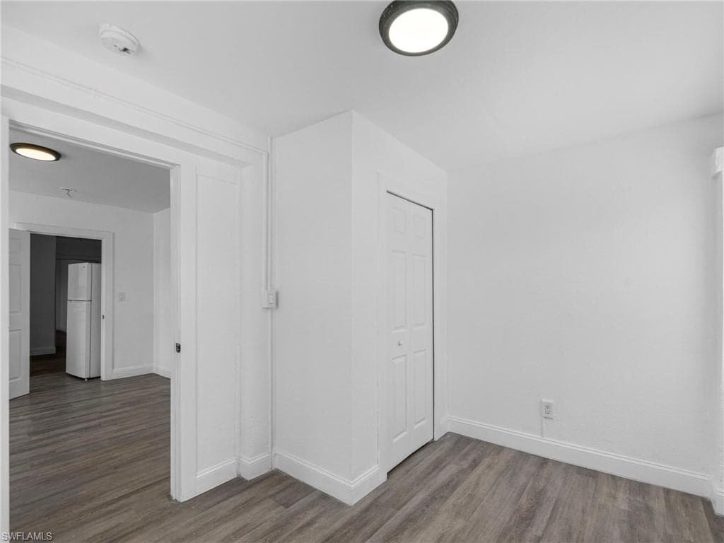 Unfurnished room with dark wood-style flooring and baseboards