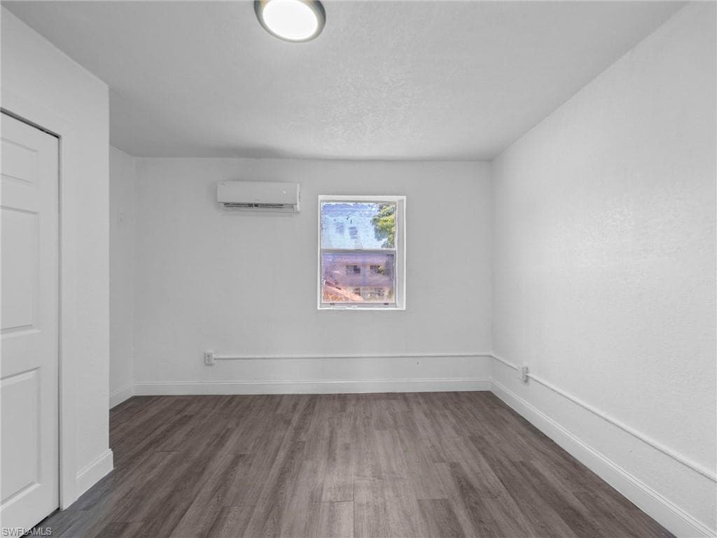 Spare room with dark wood-style floors and baseboards