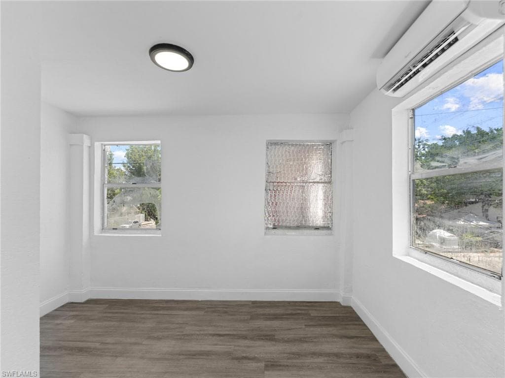 Empty room with a wall mounted air conditioner and wood finished floors