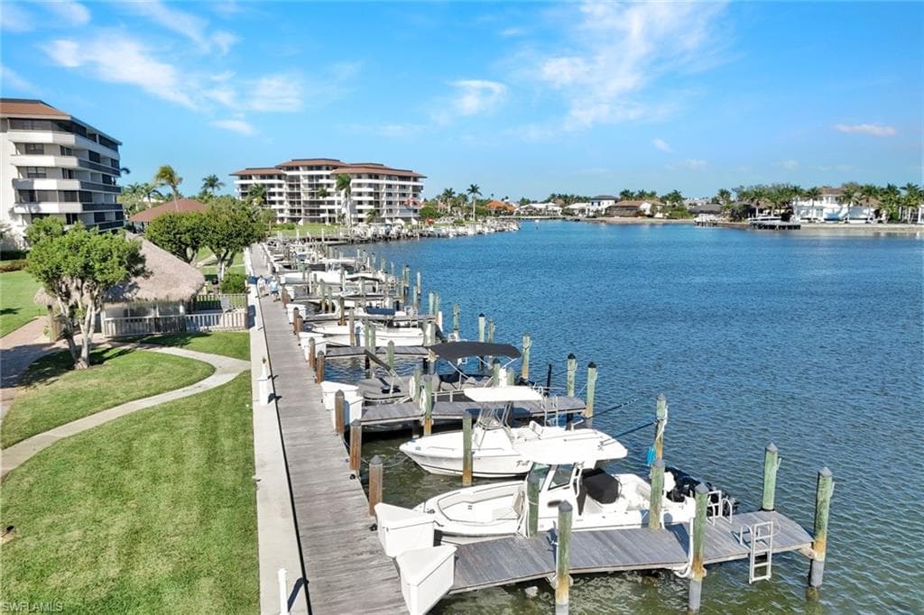 Dock area with boat lift, a water view, and a lawn