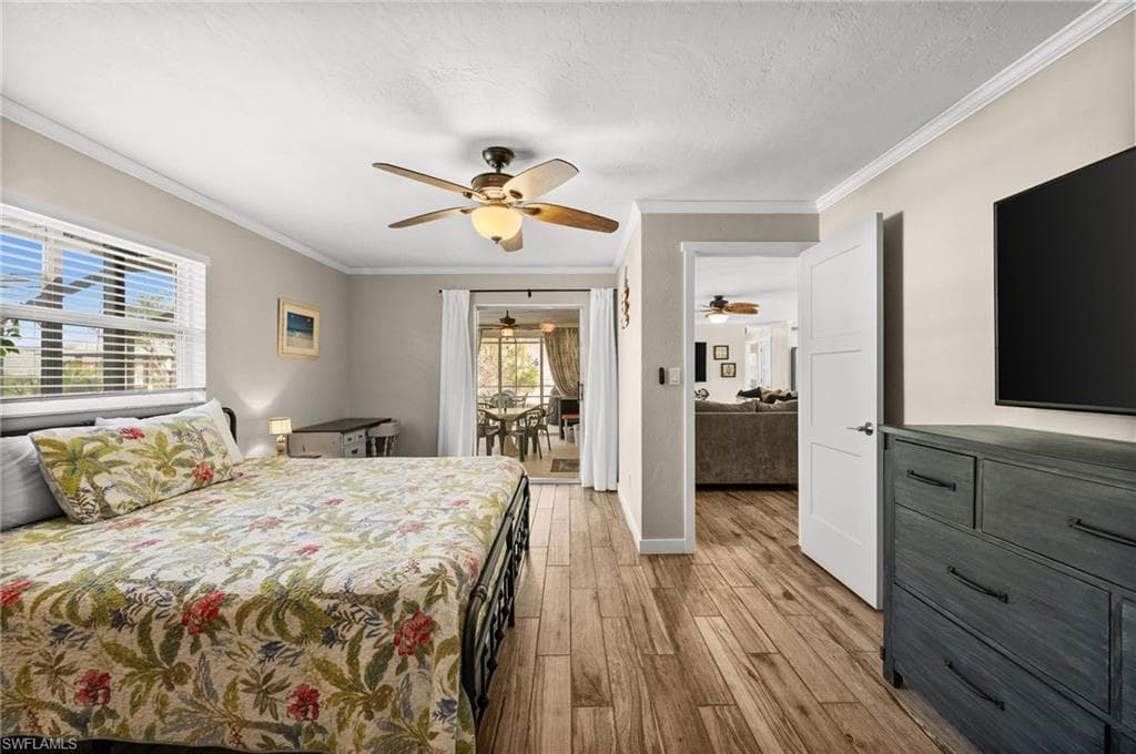 Bedroom with ornamental molding, access to outside, light wood-style flooring, and ceiling fan