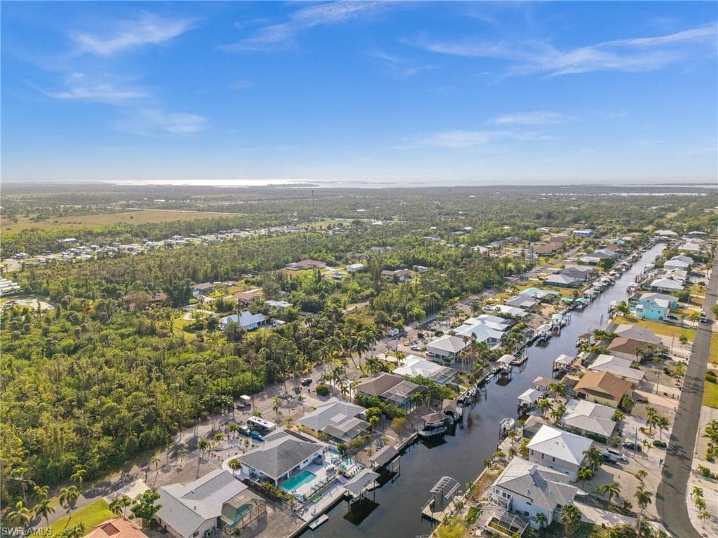 Aerial view of property and surrounding area featuring nearby suburban area and a nearby body of water
