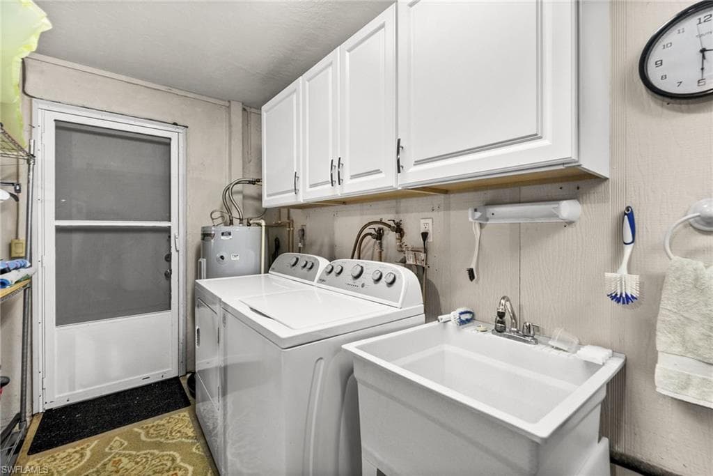 Washroom featuring washer and dryer, water heater, and cabinet space