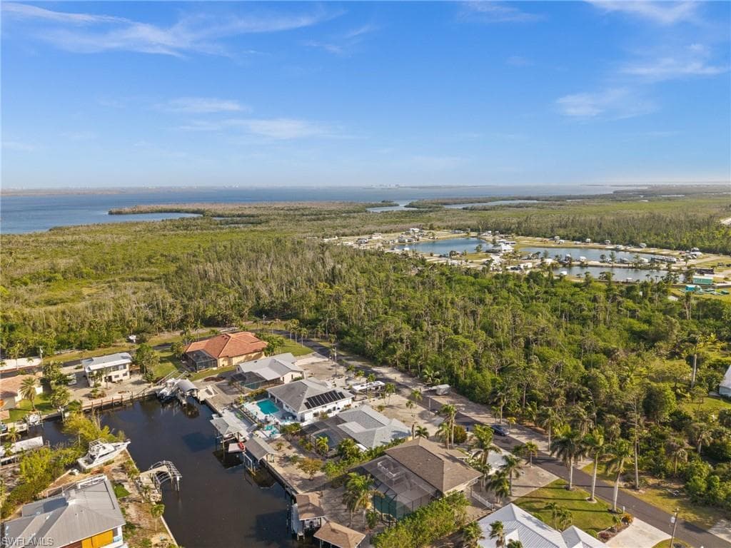 View of property location with a nearby body of water and a heavily wooded area
