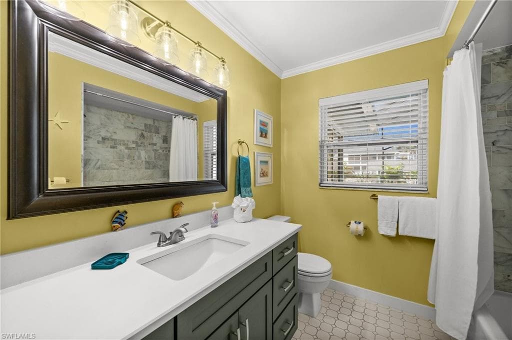 Bathroom featuring vanity, shower / bath combination with curtain, and ornamental molding