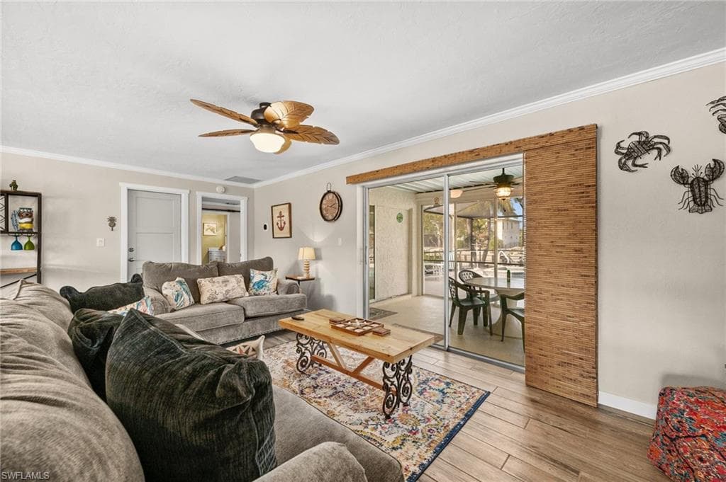 Living area featuring crown molding, light wood finished floors, and ceiling fan