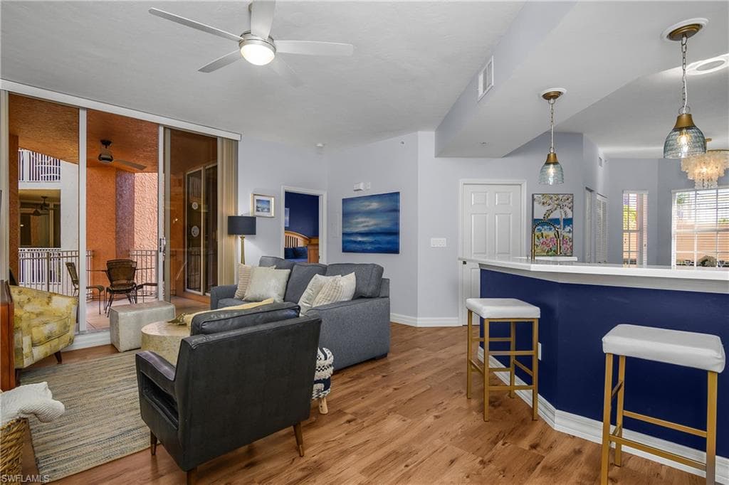Living room with light wood-type flooring, a chandelier, and ceiling fan