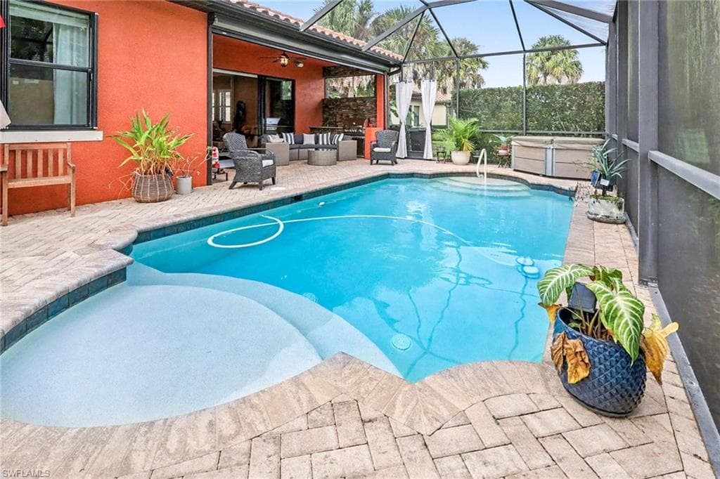 Outdoor pool with a patio area, an outdoor hangout area, glass enclosure, a sunroom, and a hot tub