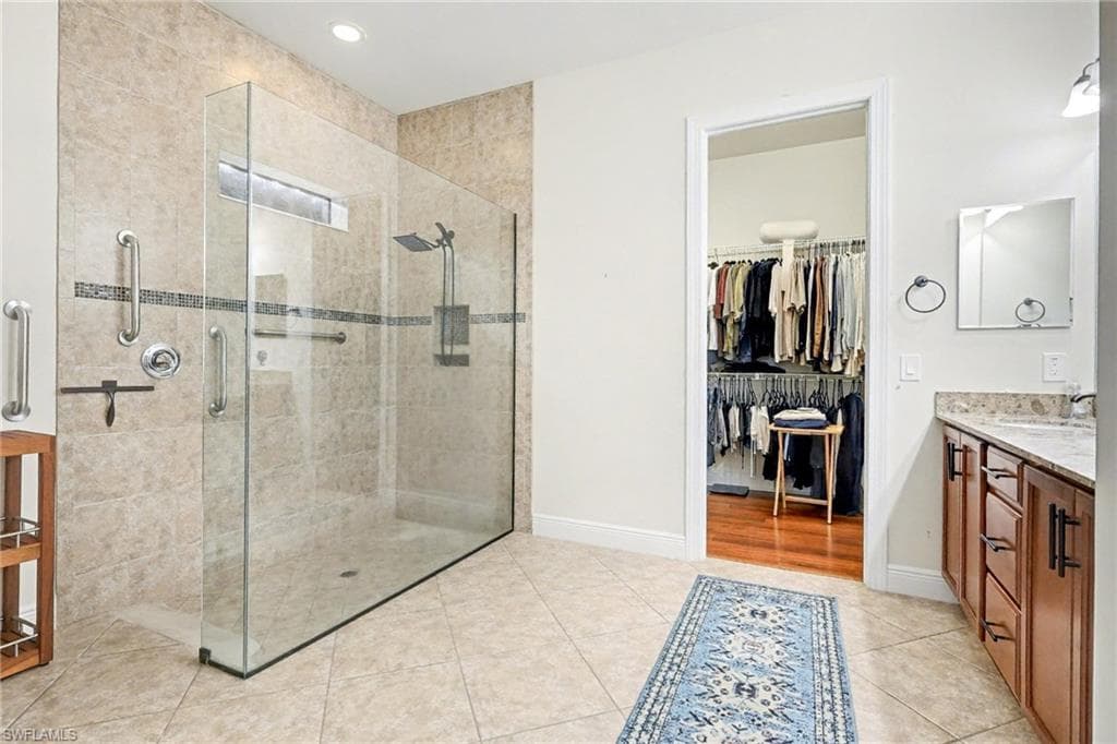 Full bathroom with vanity, a spacious closet, a shower stall, light tile patterned flooring, and recessed lighting