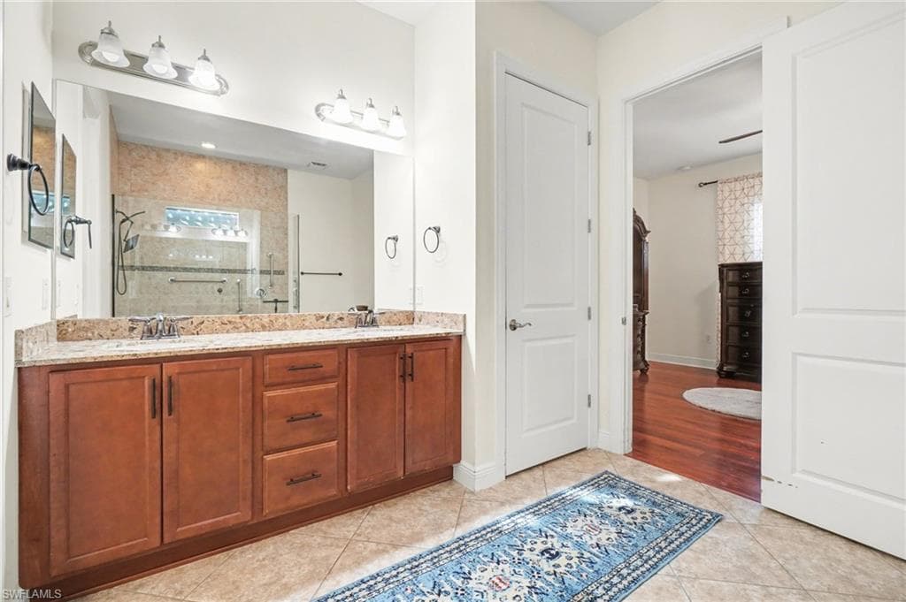 Full bath with double vanity, a shower stall, and light tile patterned floors