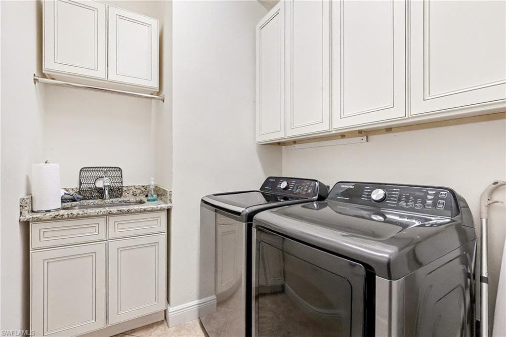 Laundry room with cabinet space, separate washer and dryer, and light tile patterned floors