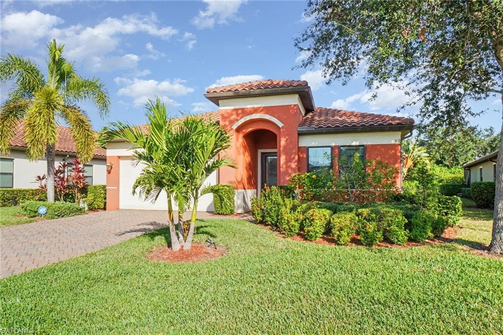 Mediterranean / spanish-style home with a garage, decorative driveway, a tile roof, a front lawn, and stucco siding